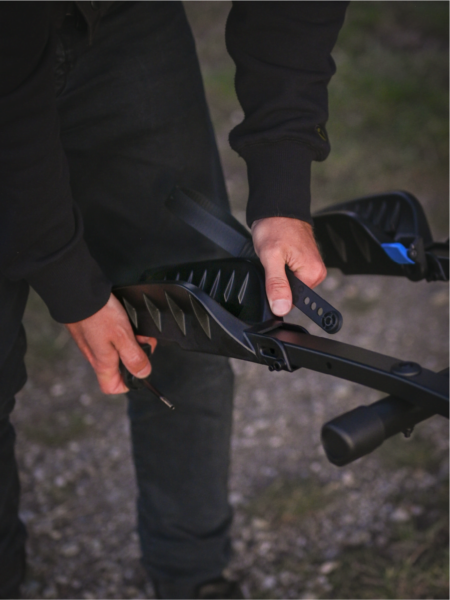 A man is adjusting the position of a wheel tray on the Enduro bike rack