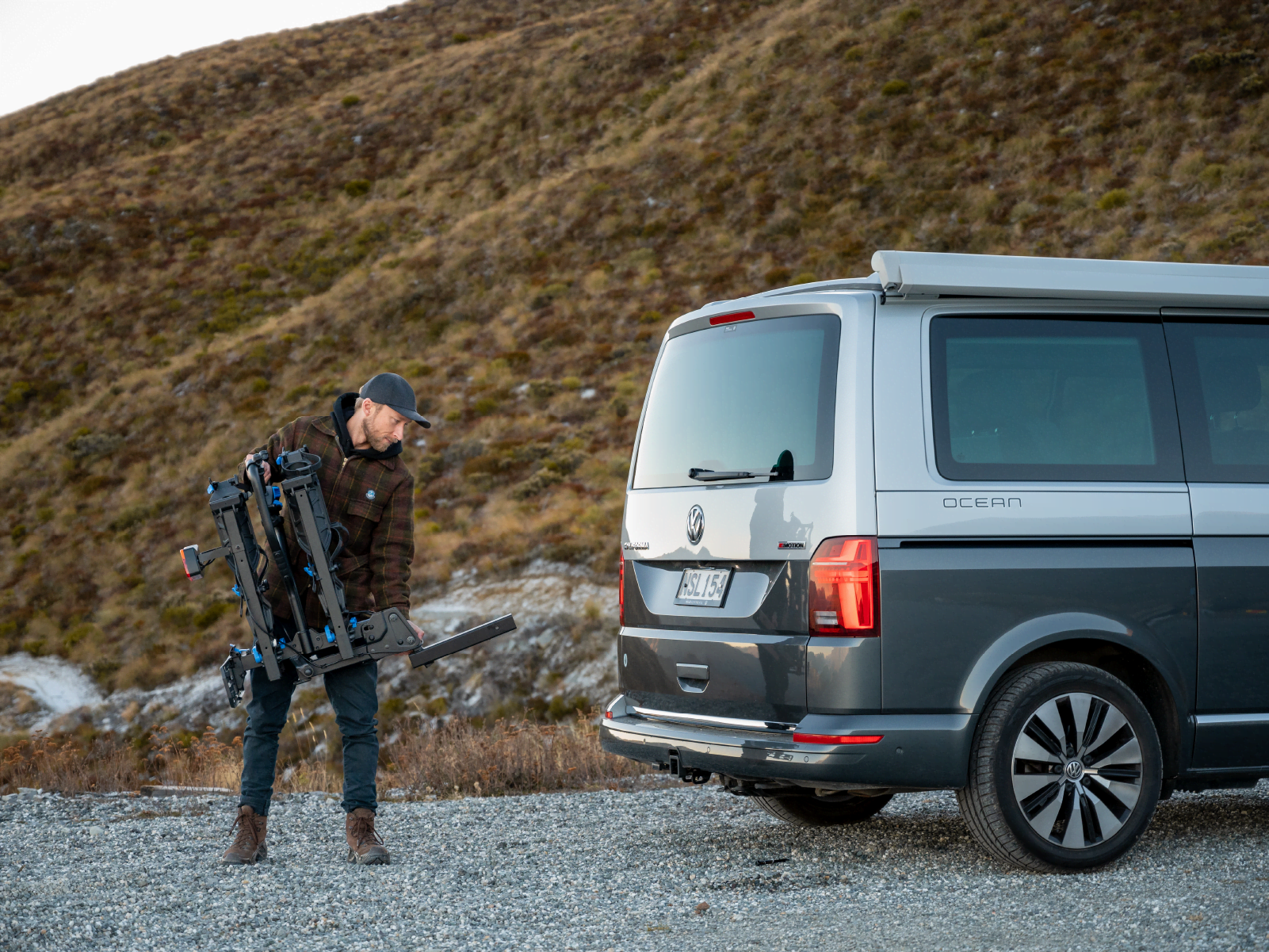 A man is holding the Ezigrip E-Rack 2 Pro ebike rack which is neatly folded and close to his body as he goes to mount the rack to a van.