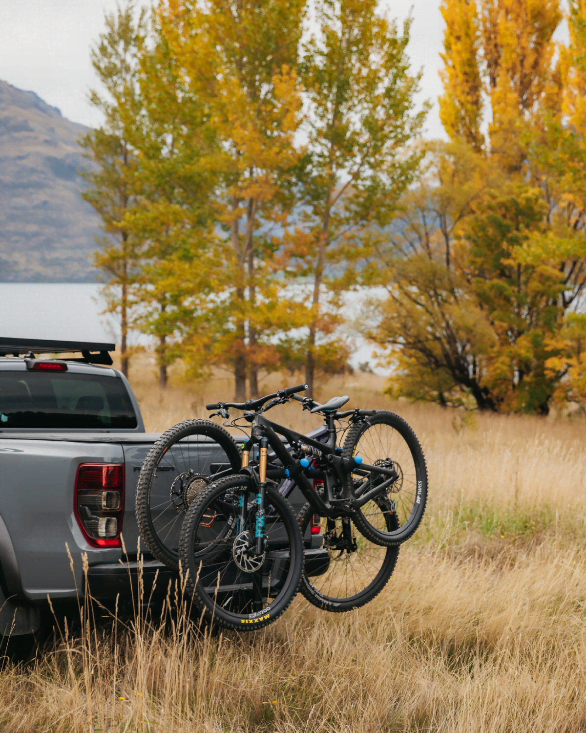 An ezigrip advantage 2 bike rack is mounted to a ute with two mountain bikes strapped to the rack and a lake visible in the distance