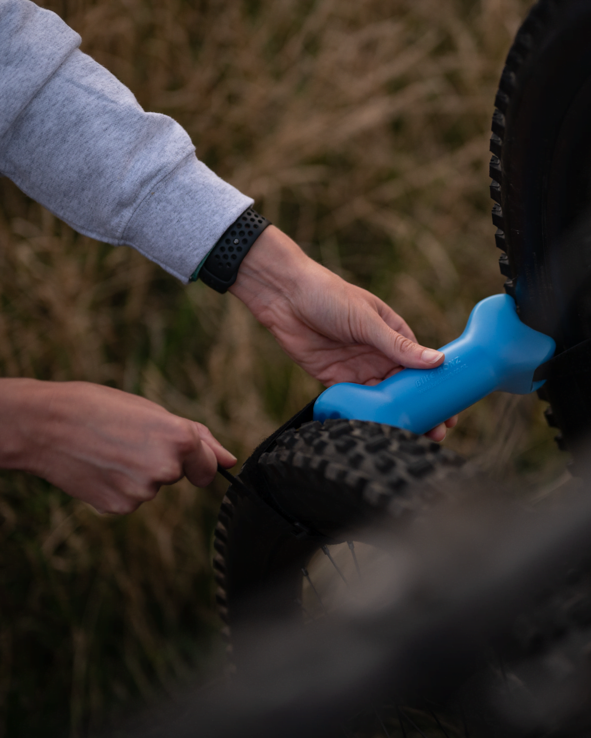 A woman is installing a bike bone between the tires of two neighboring bikes to keep them separated