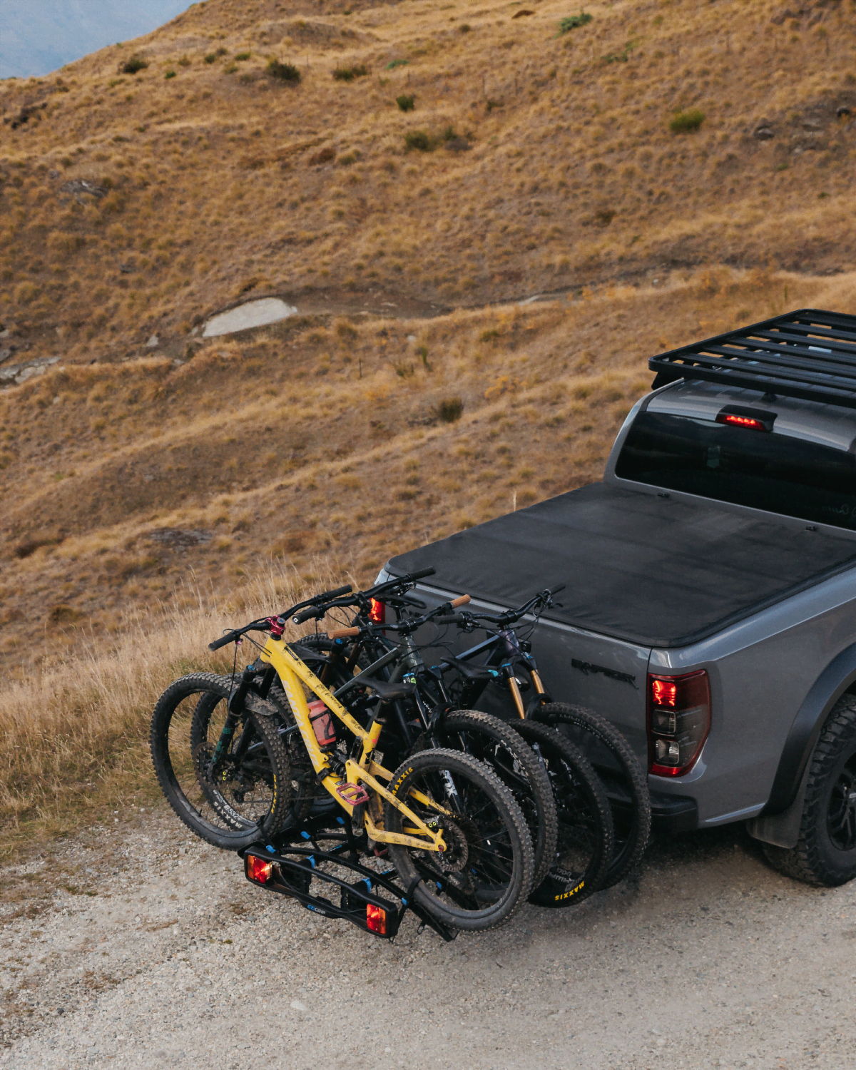 A view of an Enduro 4 bike rack with 4 mountain bikes loaded on the bike rack on the back of a ute as it drives up a mountain road