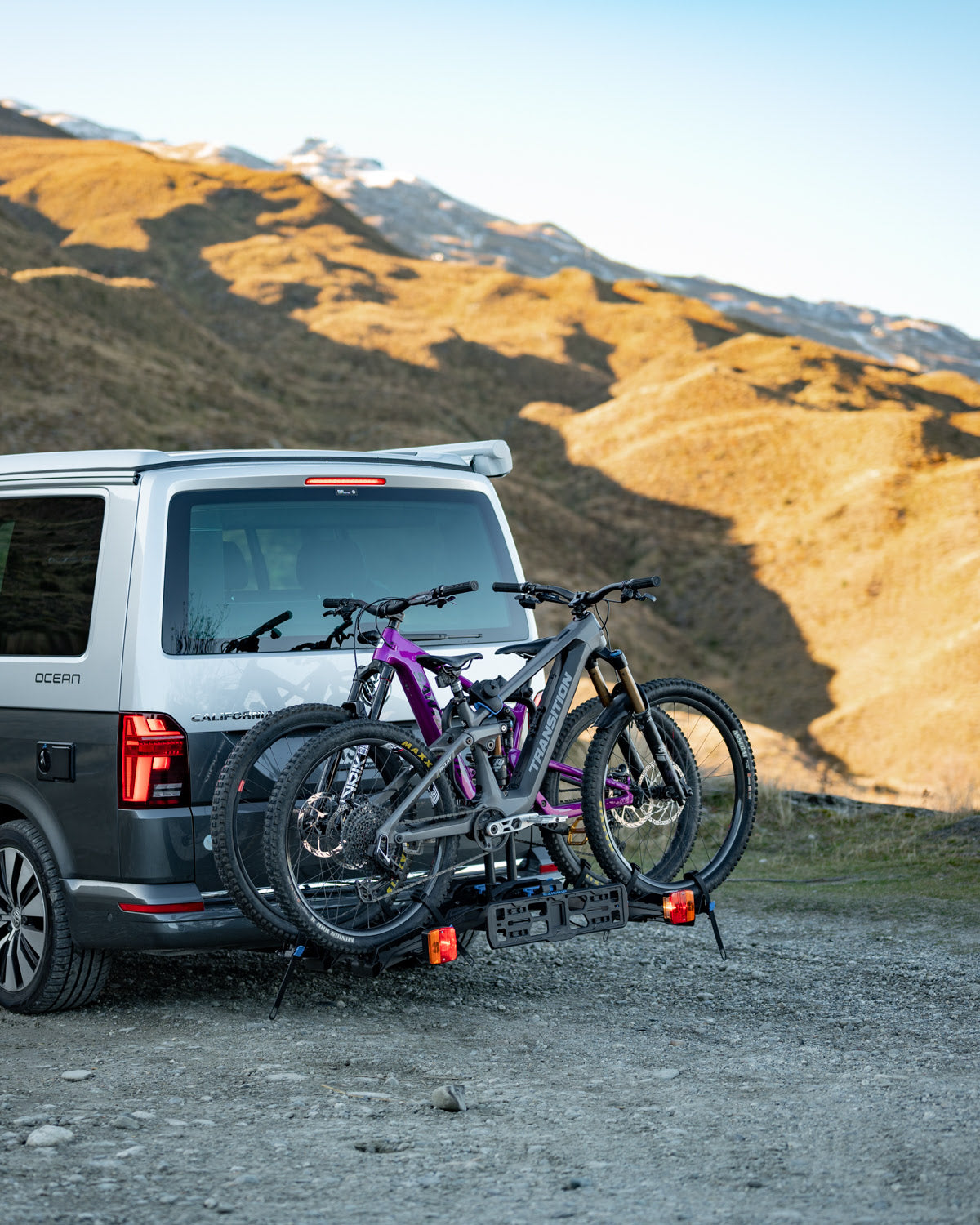 Two ebikes are loaded on the E-Rack 2 Pro hitch mounted ebike rack attached to a van with the New Zealand Southern Alps visible in the background