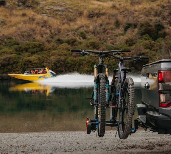 An Enduro 2 bike rack with two mountain bikes strapped to the rack is viewed from the side, mounted to a ute. There is generous spacing between the mountain bikes.