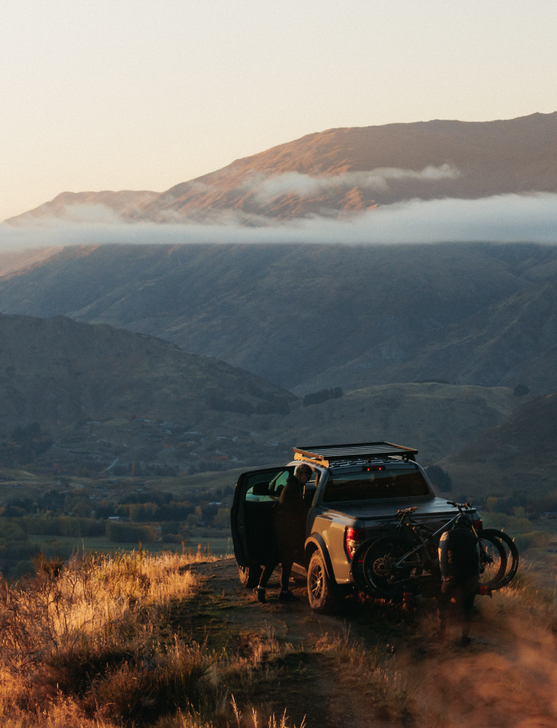 A man is installing a bike onto a bike rack with the new zealand mountains in the background