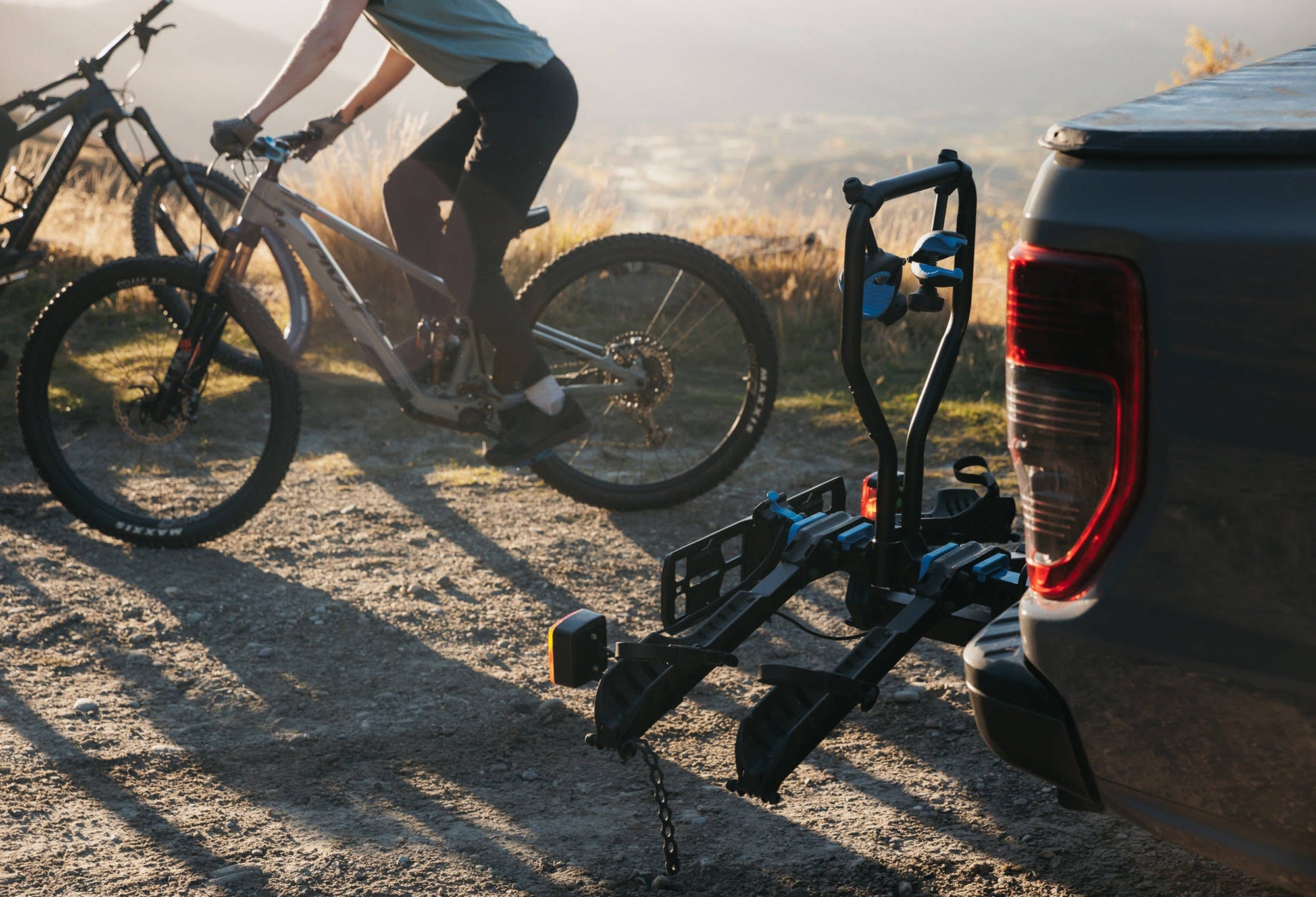 An Ezigrip E-Rack 2 sits atop a towball of a ute with a emtb rider in the background