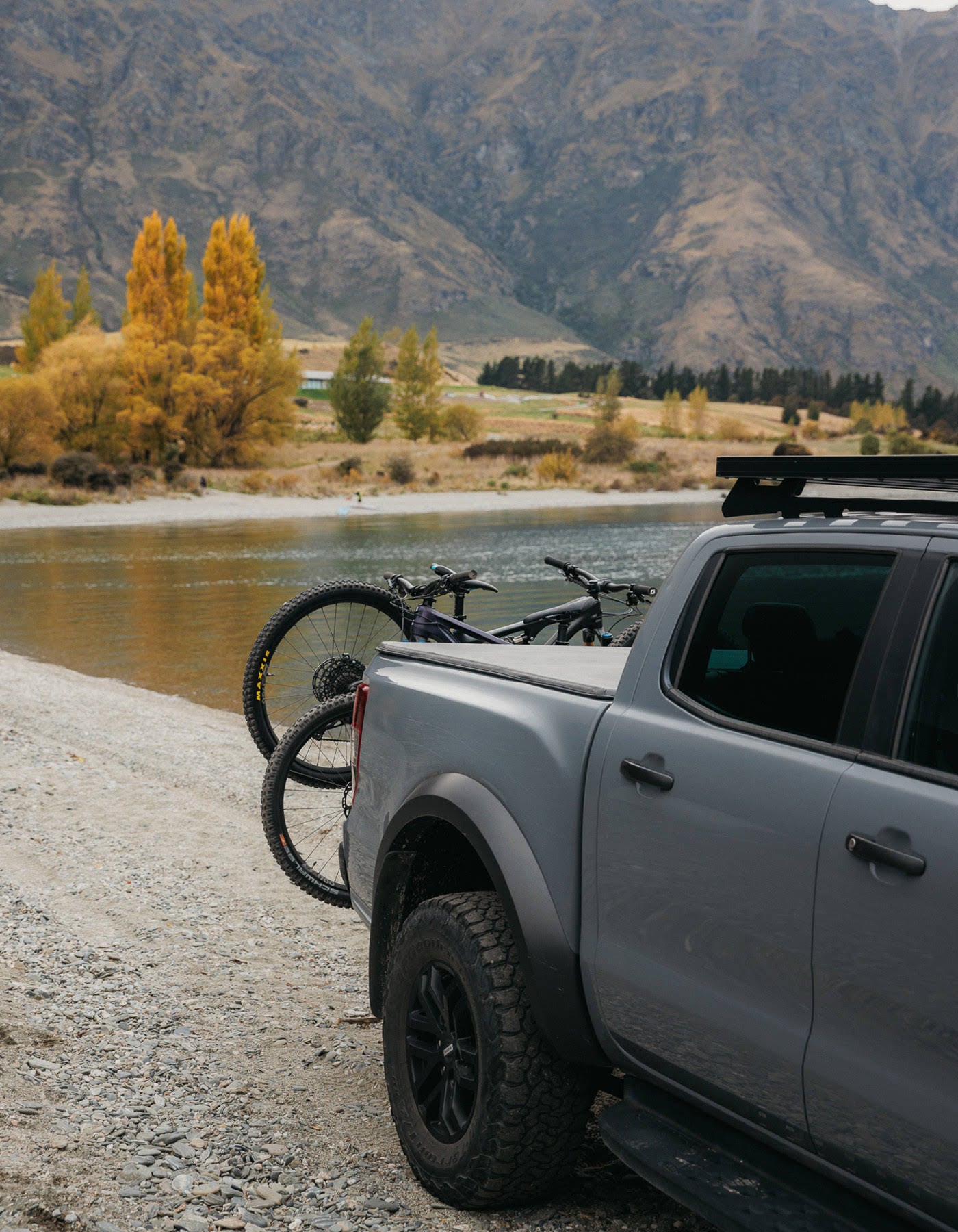 Two bikes are clearly visible on the back of a ute with mountains above. The bikes sit on an Ezigrip Advantage 2 bike rack.