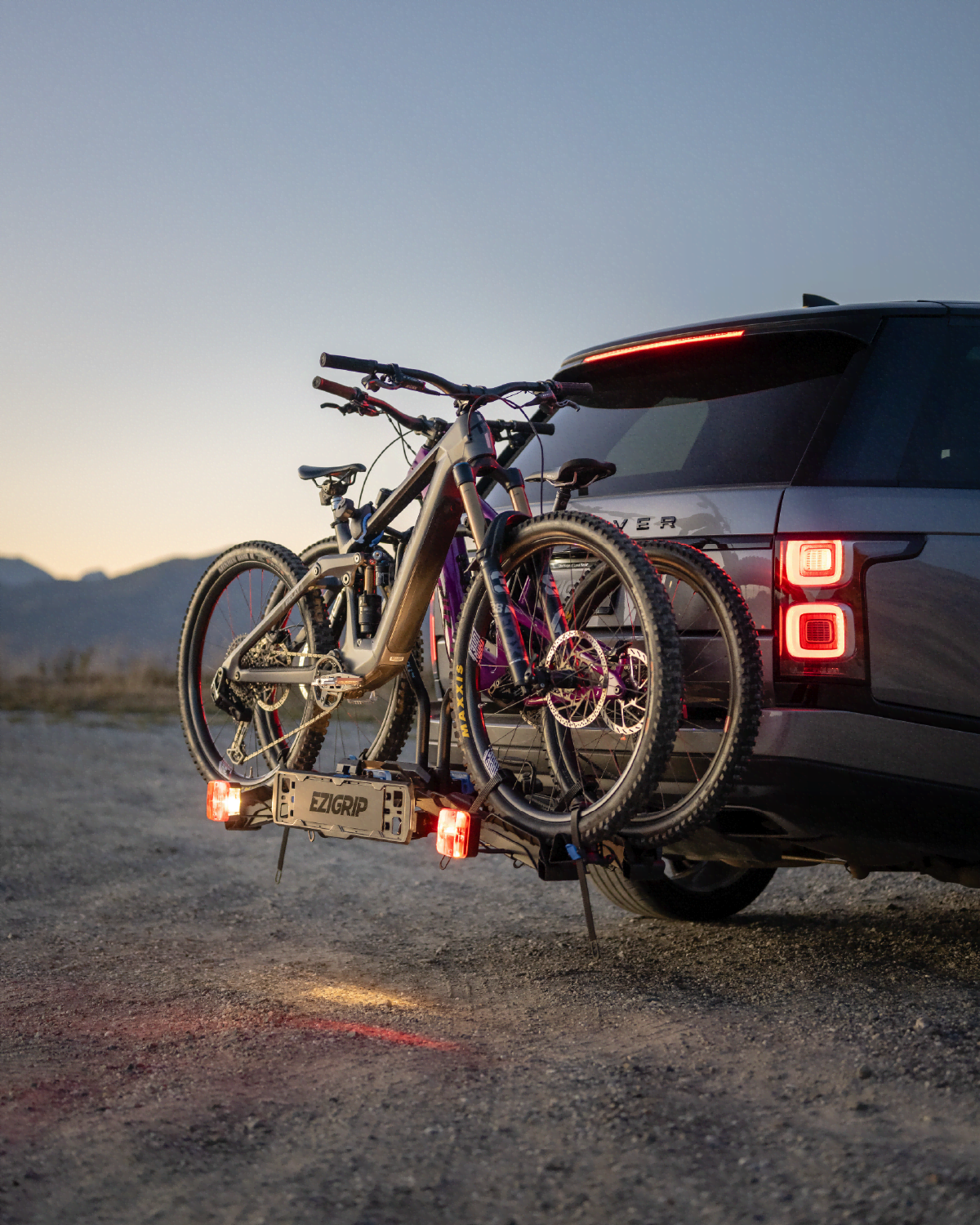 Electric bicycles on a bike rack attached to a Range Rover in a desert setting