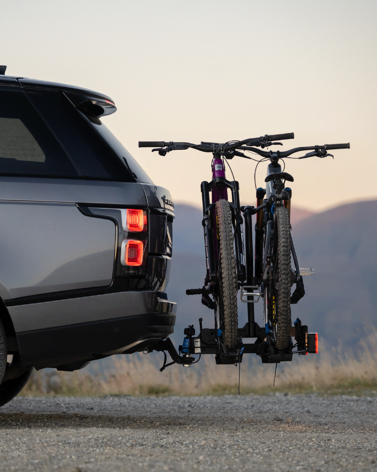 electric bikes on an Ezigrip E-Rack 2 Pro towball mounted bike rack attached to a car with mountains in the background
