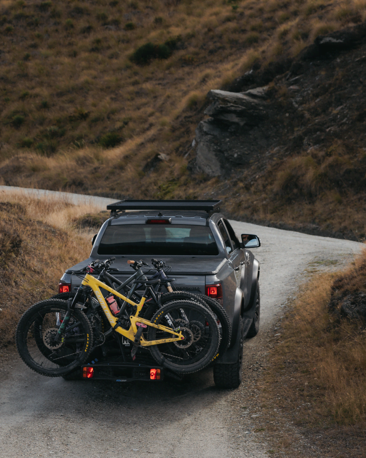 An Enduro 4 bike rack on the back of a ute has 4 mountain bikes strapped to bike rack as it travels up a mountain road
