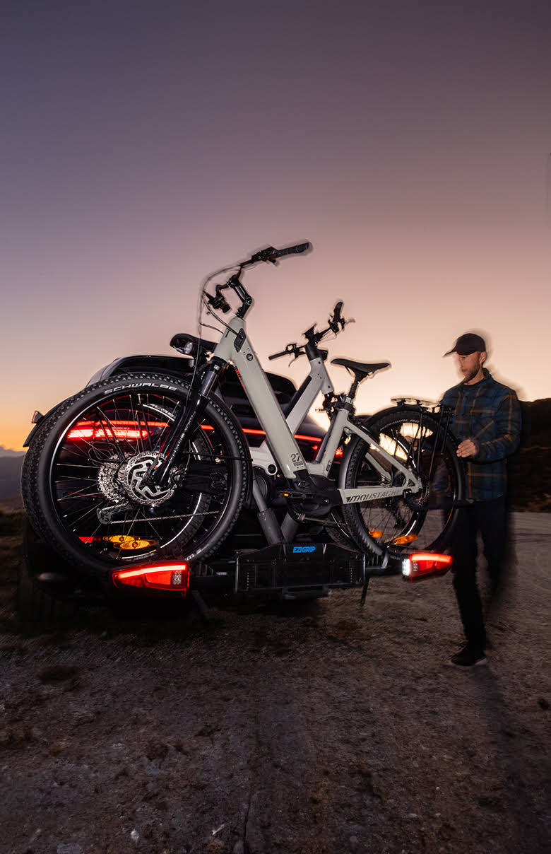 An Ezigrip E-volve 2 is mounted to a Porsche SUV with the LED tail lights of the rack clearly glowing