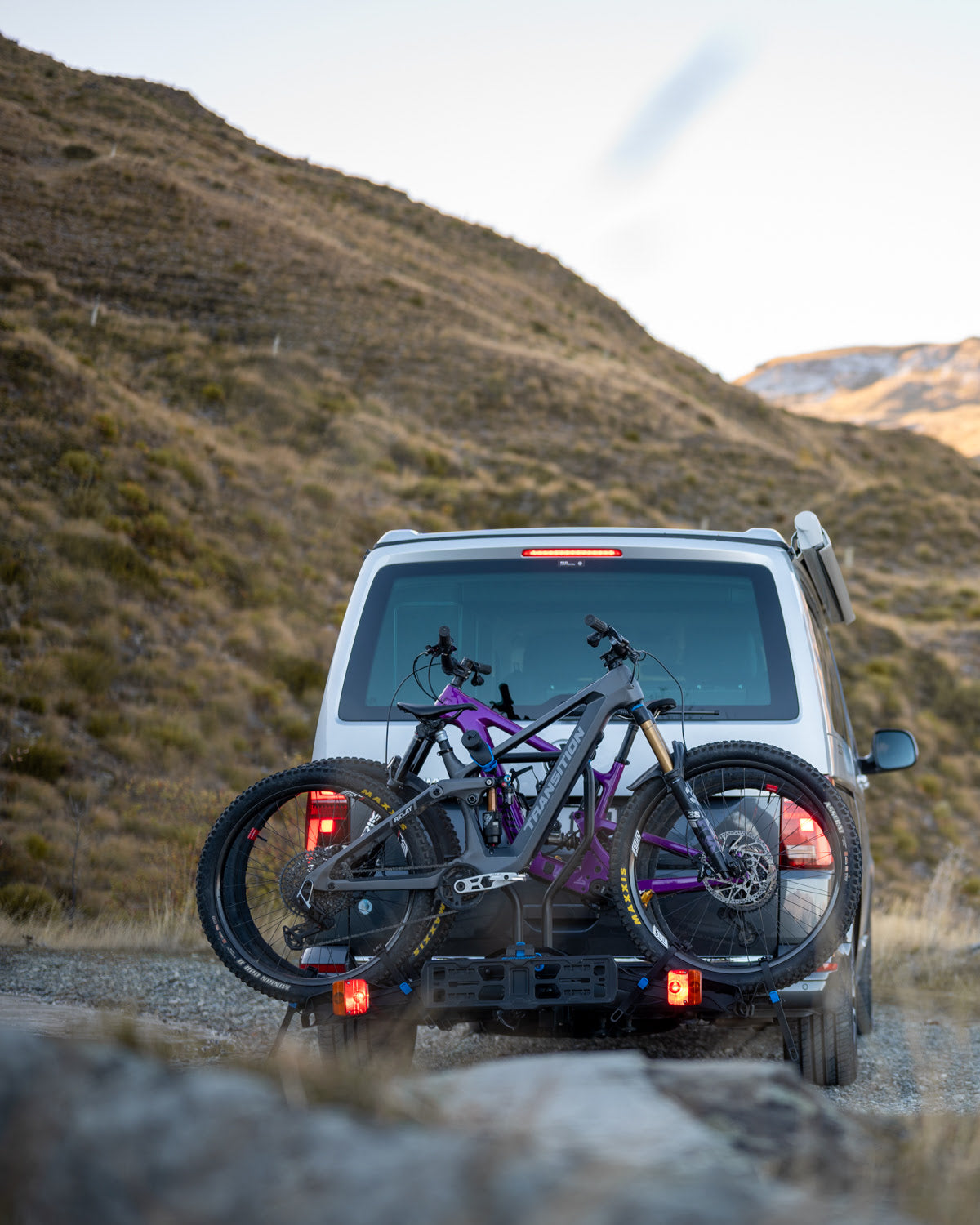 The Ezigrip E-Rack 2 ebike rack is loaded with two ebikes and mounted to a van with the mountains of New Zealand in the background